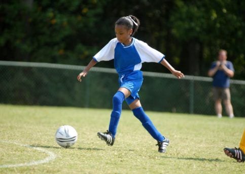 african american girl playing soccer with determination