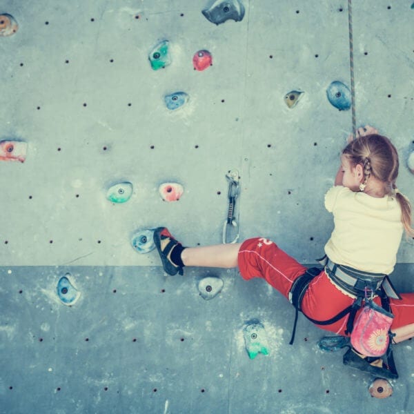 little girl climbing a rock wall in kid-friendly class