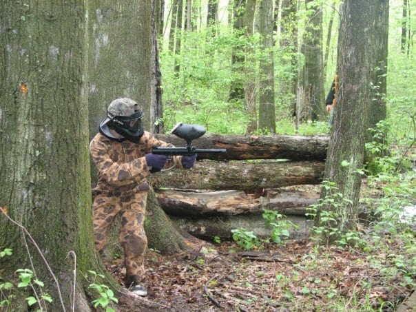 paintball player crouching in woods