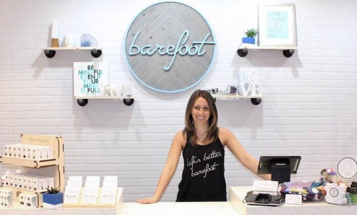 Cashier in front of Barefoot logo