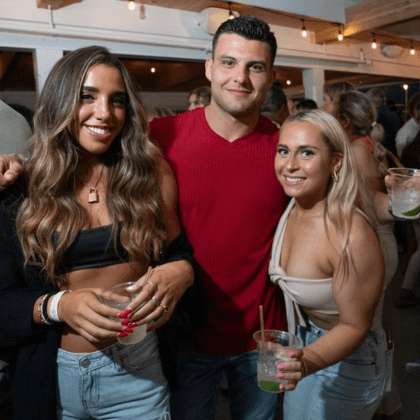 Young Adults Posing with Drinks at outdoor bar.